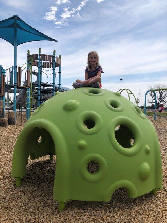 Girl sitting on top of spherical play structure