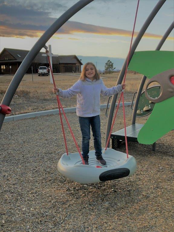 Girl on disc swing at Wright Park in Broomfield Colorado