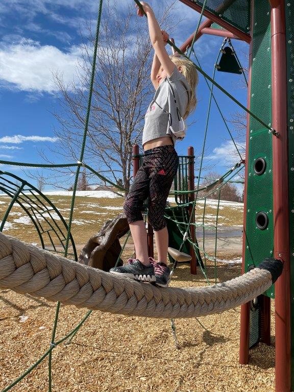 Girl climbing across thick rope at playground