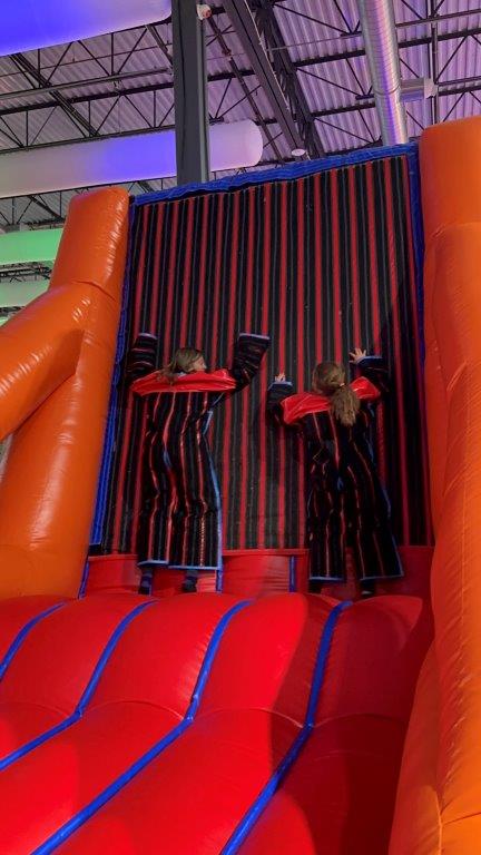 bounce empire is for adults too. Photo of Mom and child jumping on to the velcro wall together.