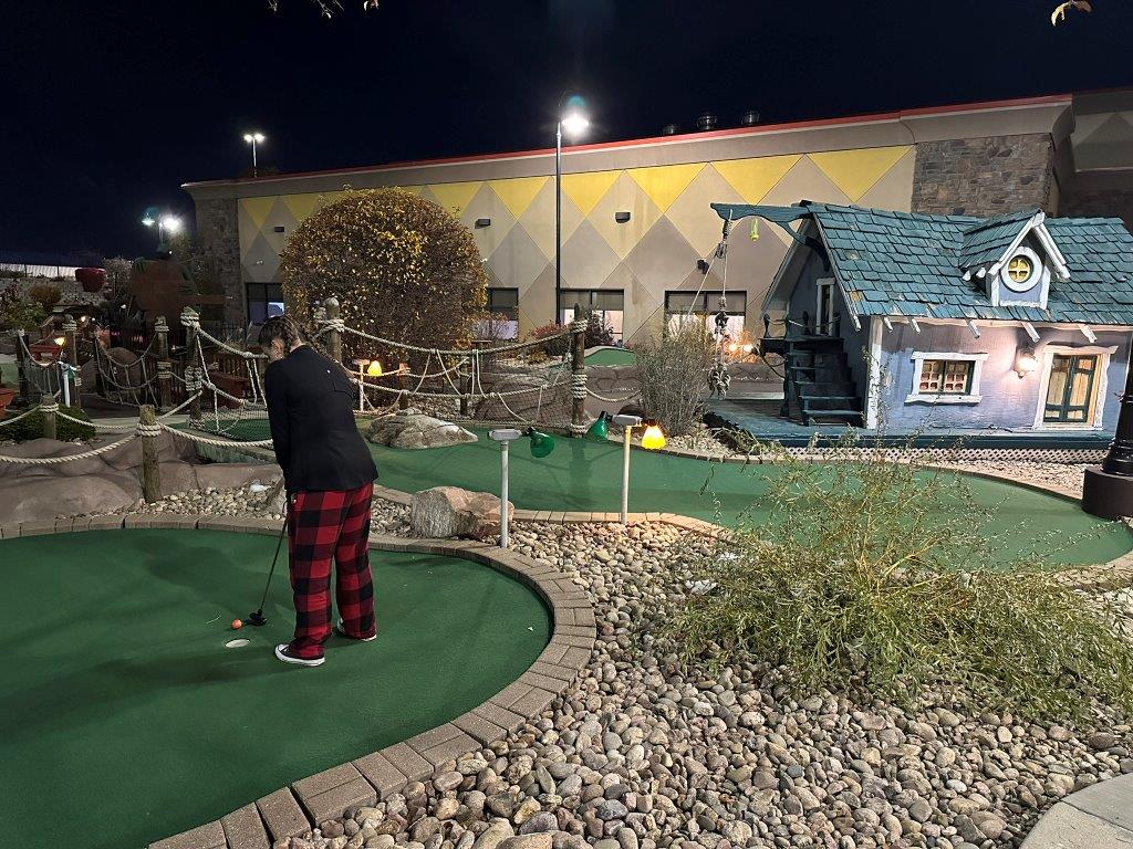 girl playing miniature golf at night